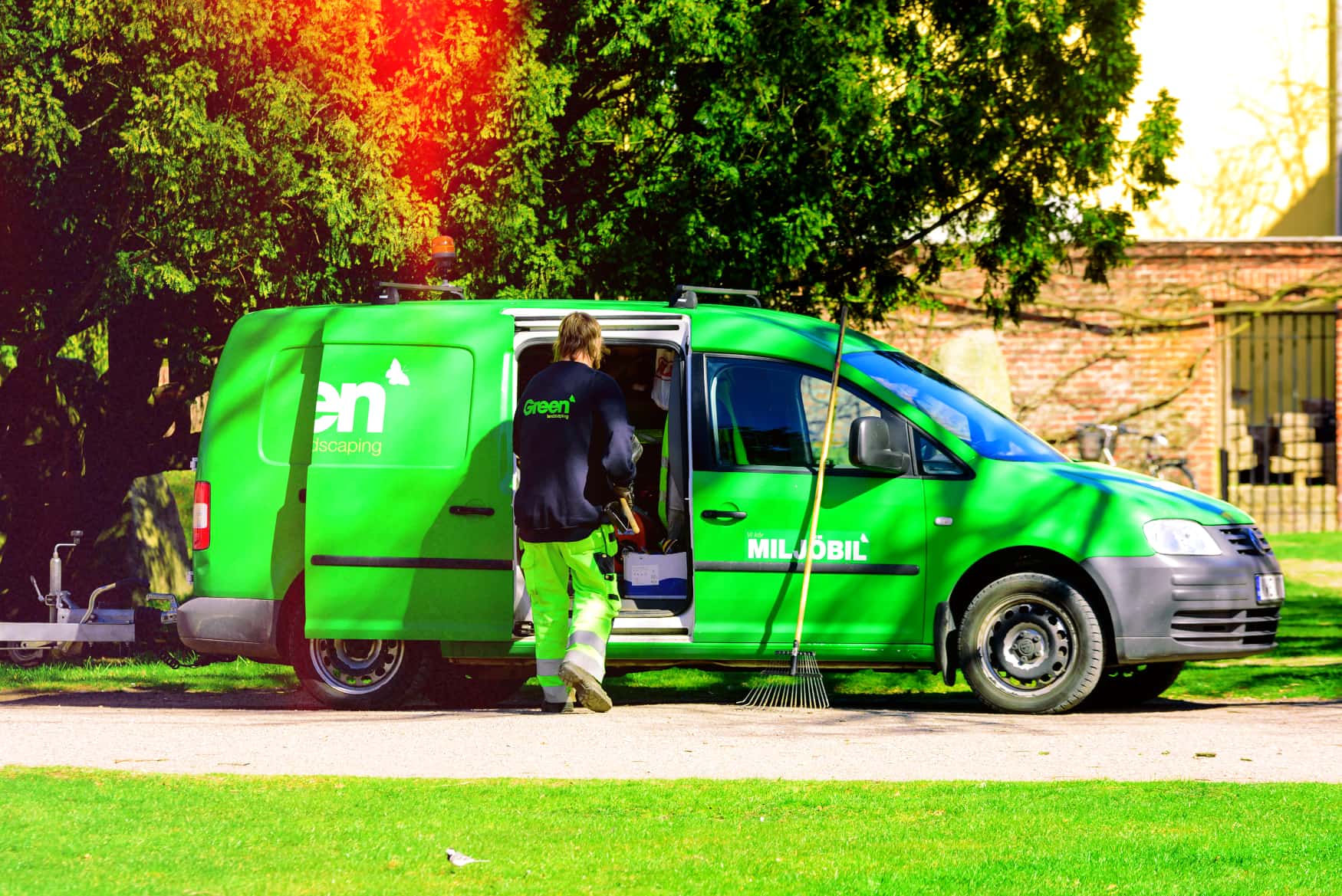 GPS tracking solutions for landscape and grounds maintenance fleets Landscaping professional accessing tracked green maintenance van for optimized grounds management operations